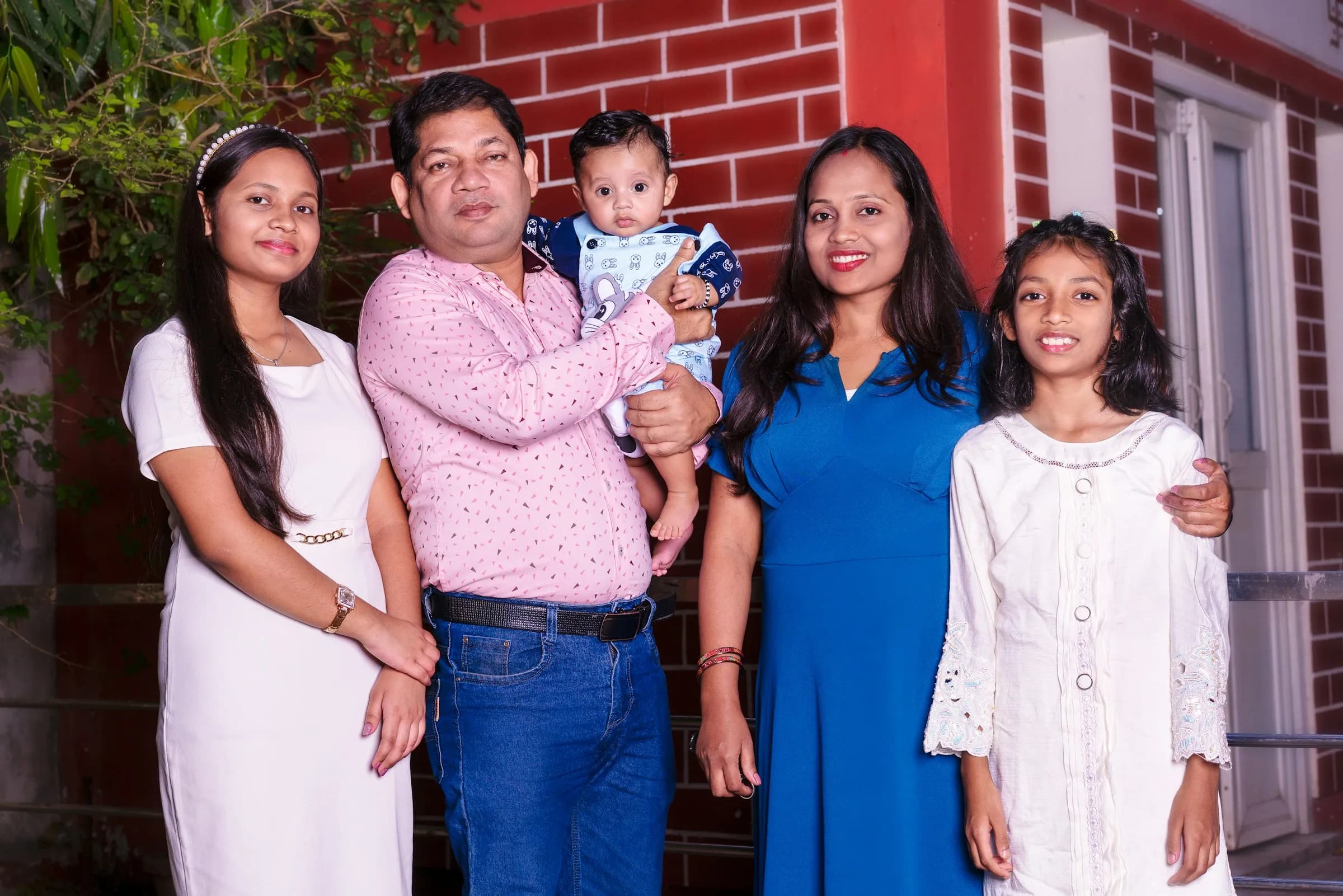 Familia de cinco con un bebé posando frente a su casa