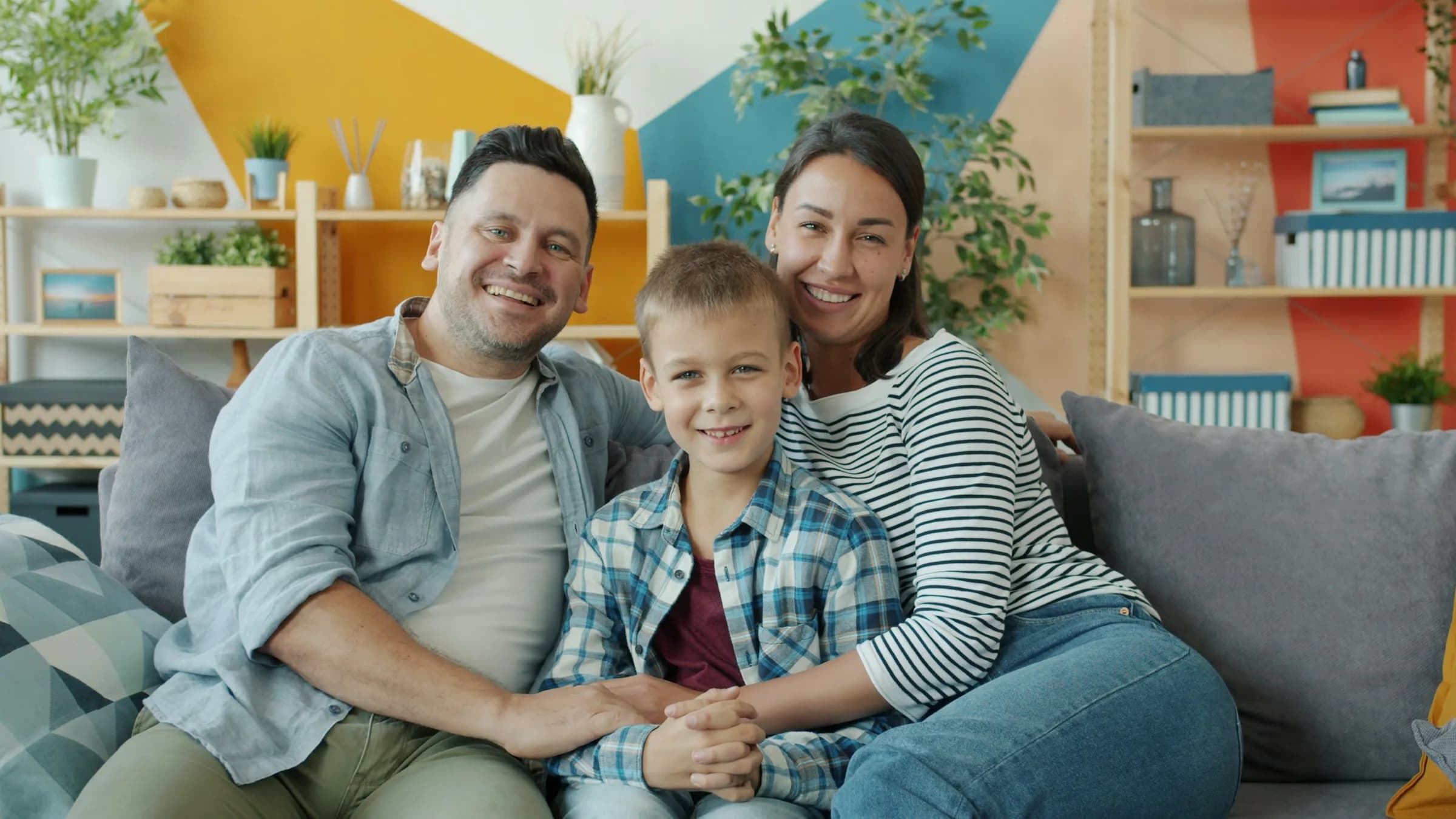 Padre, madre e hijo sonriendo sentados en el sofá de su sala